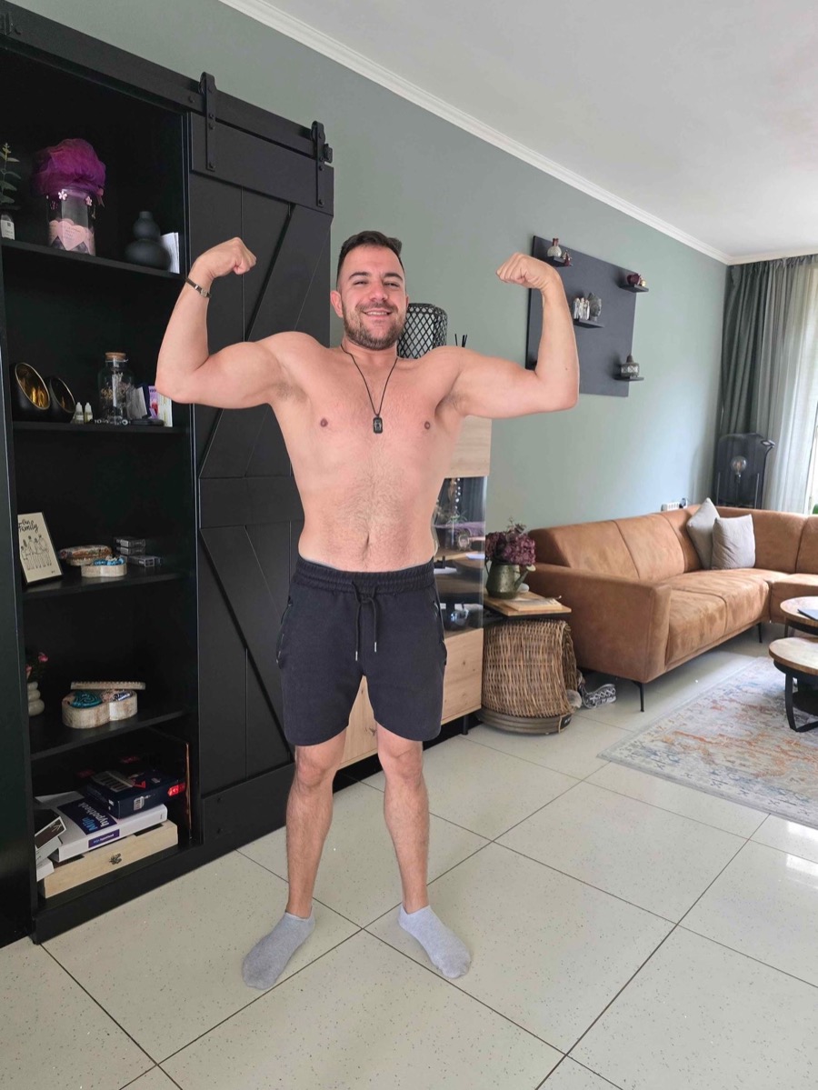 Dezelfde cliënt na het traject, lachend met dubbele biceps